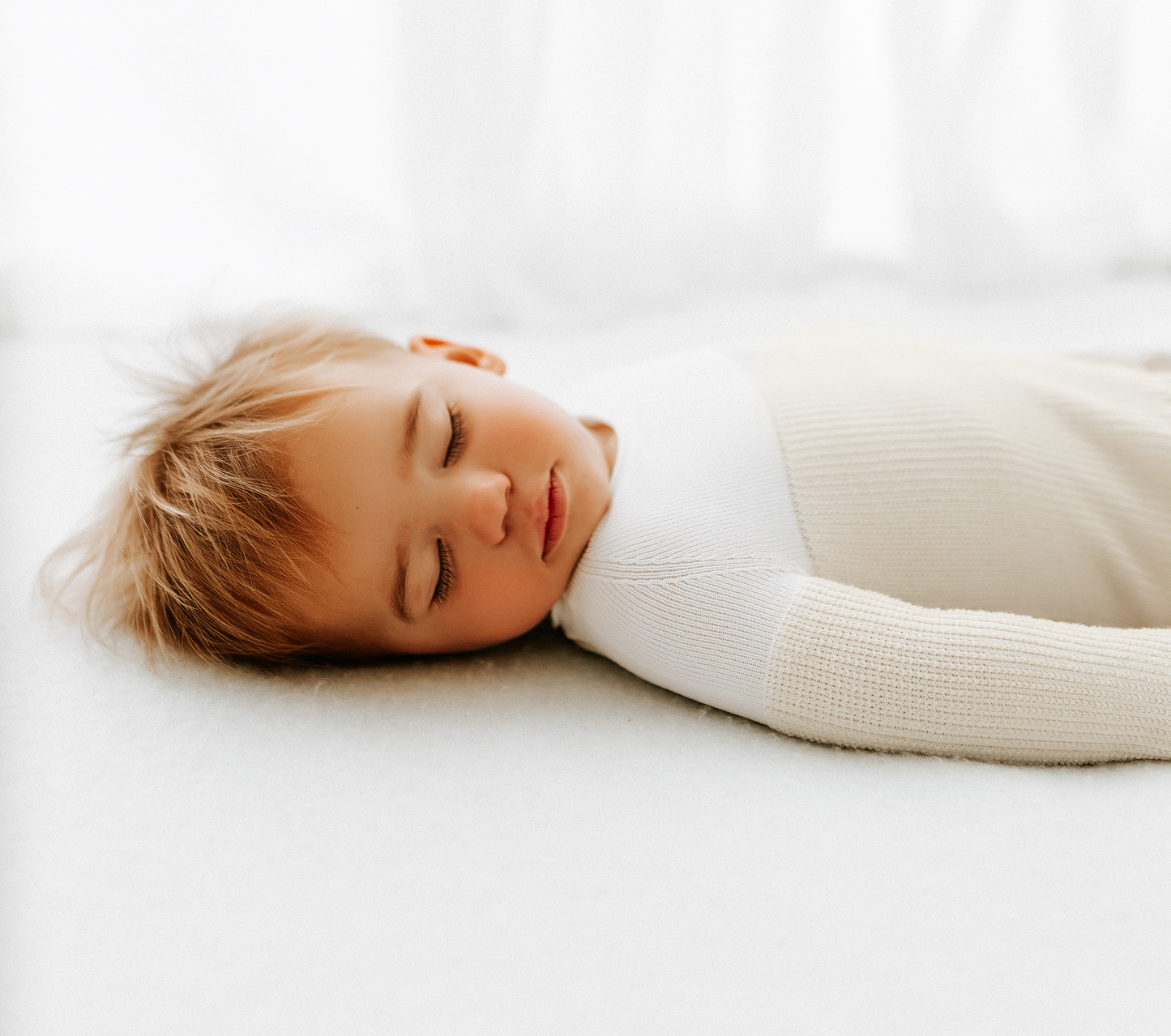 A baby sleeping in a transition sleep sack.