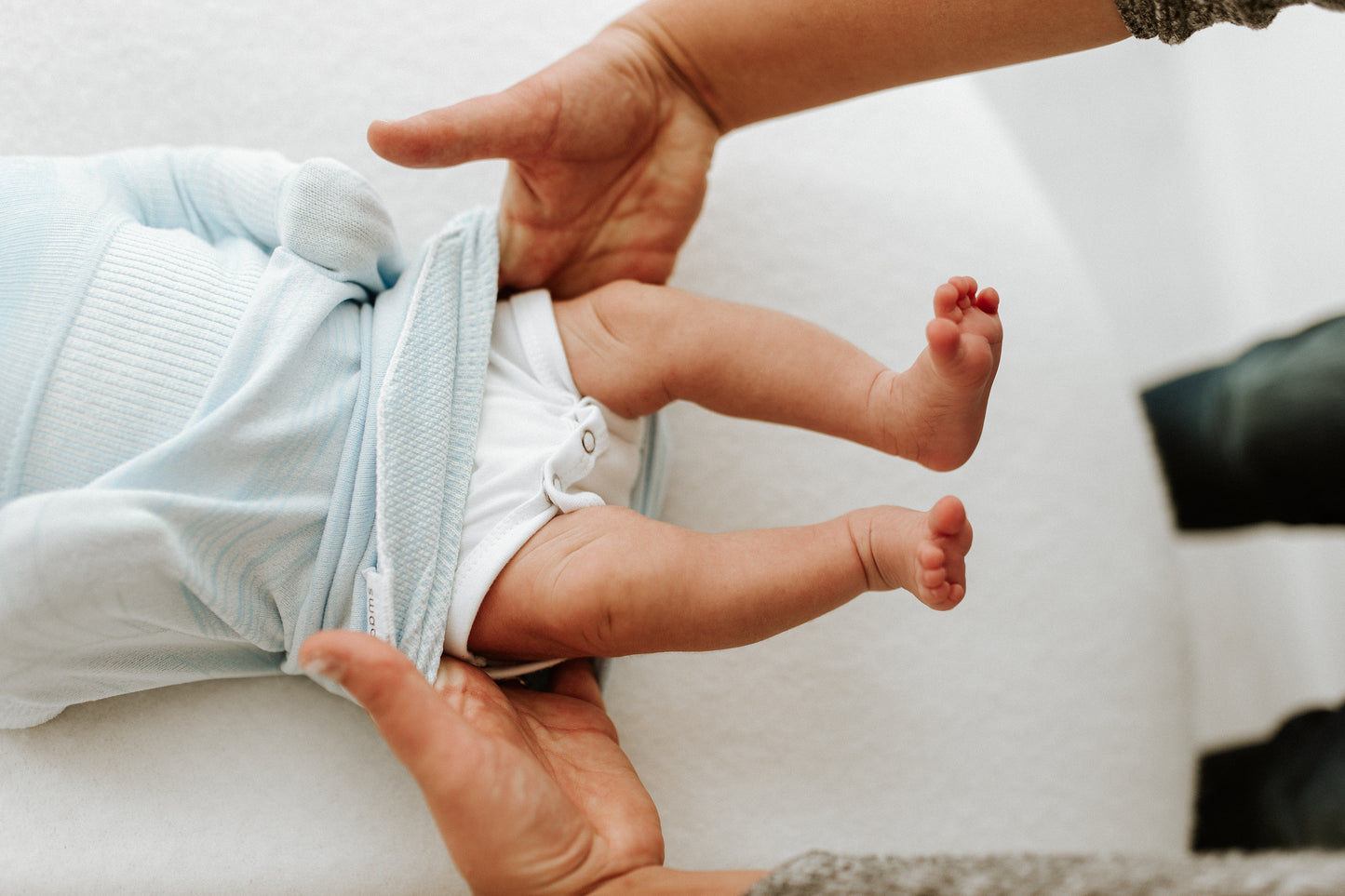 A mother accessing her baby's diaper in its sleep sack.