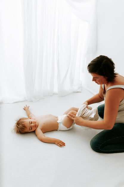 A mother putting a transition swaddle on her baby.