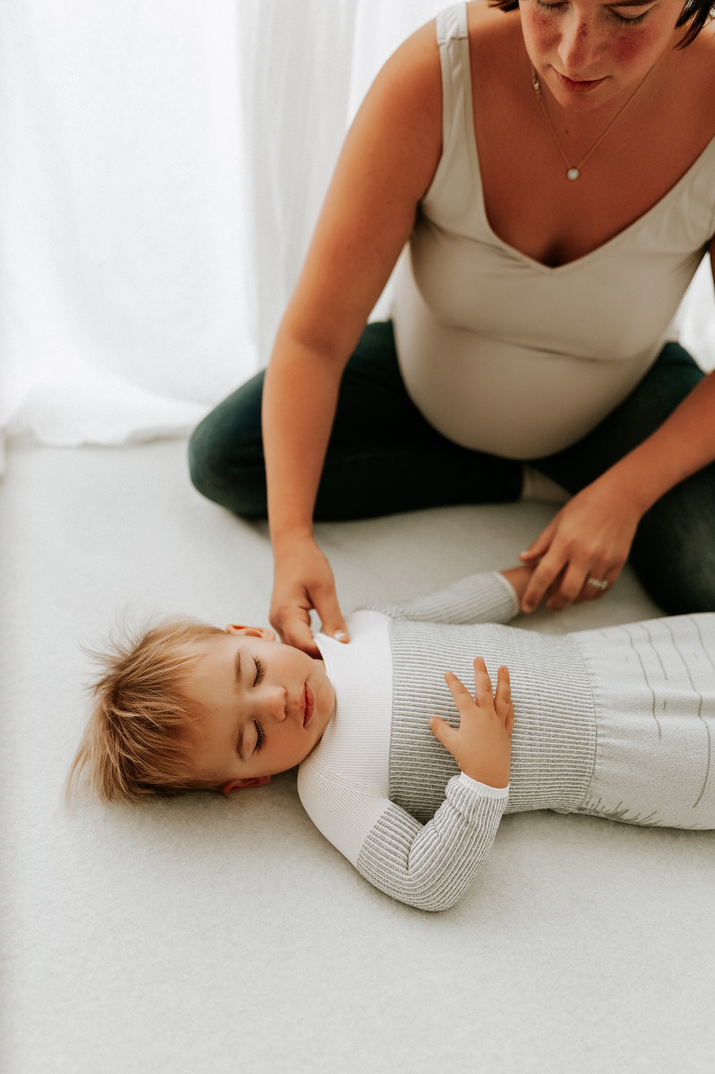 A pregnant mother putting her toddlers sleep sack on.