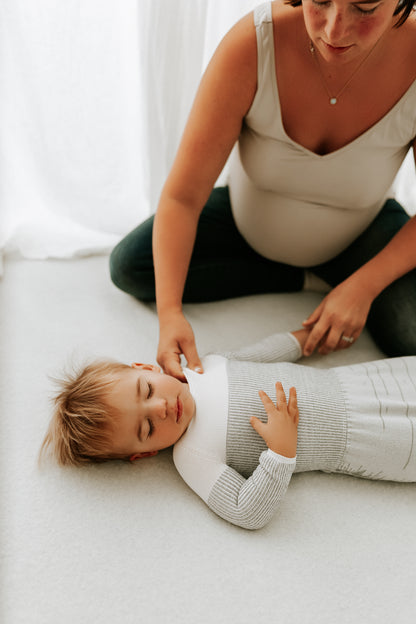 A pregnant mother putting her toddlers sleep sack on.