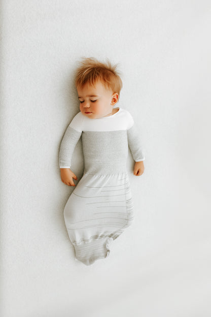 A baby sleeping in a grey transition swaddle.