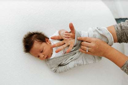 A mother putting her infant into a soft swaddle.