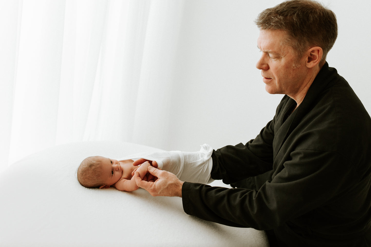 A father putting a summer sleep sack on his child.