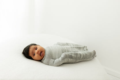 A happy baby in a baby swaddle.