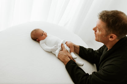 A father putting a swaddle on his preemie baby.