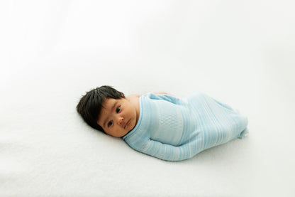 A baby partially in a swaddle.