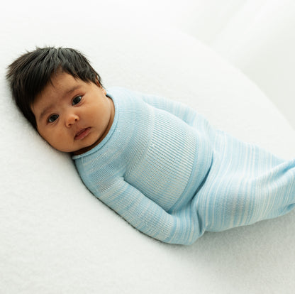 A baby resting in a blue Swaddelini.