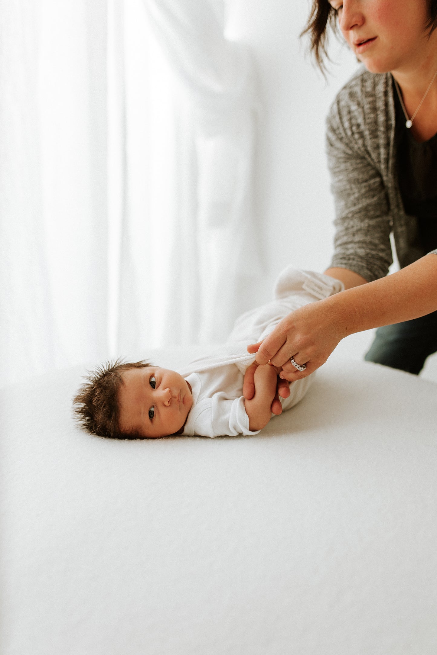 A mother putting a bamboo sleep sack on her infant.