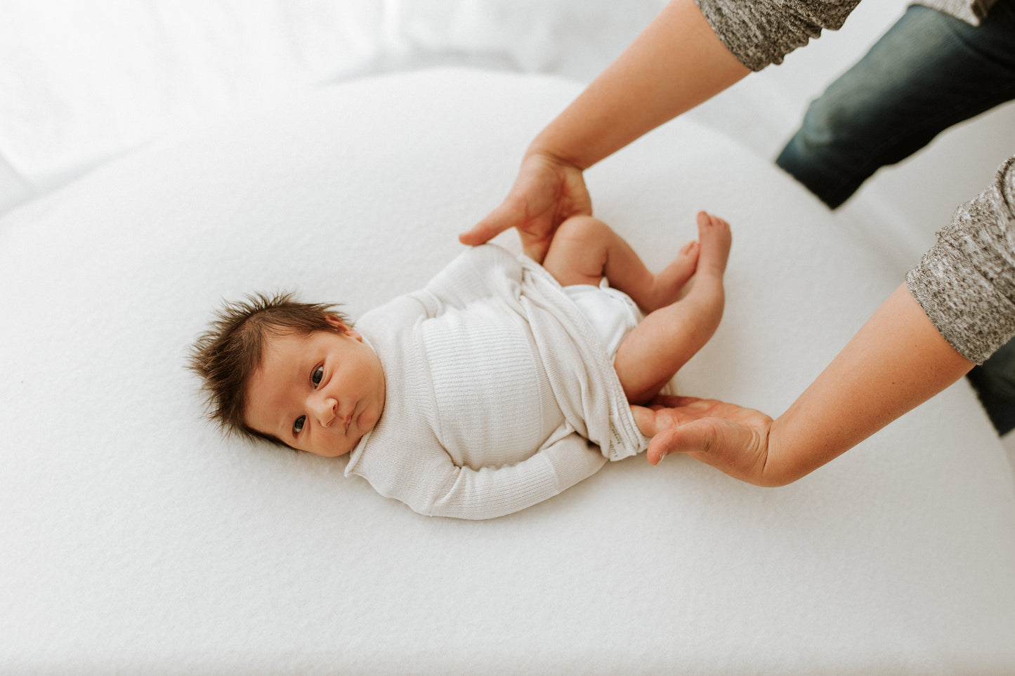 A mother accessing her baby's diaper while keeping the sleep sack on.