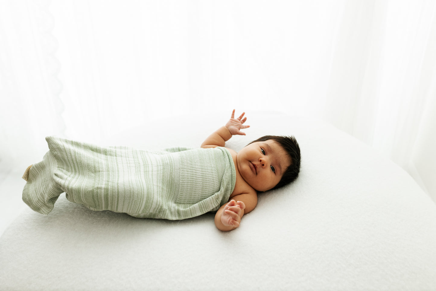 A baby resting in an infant swaddle.