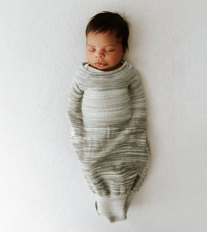 A baby sleeping in a grey swaddle.