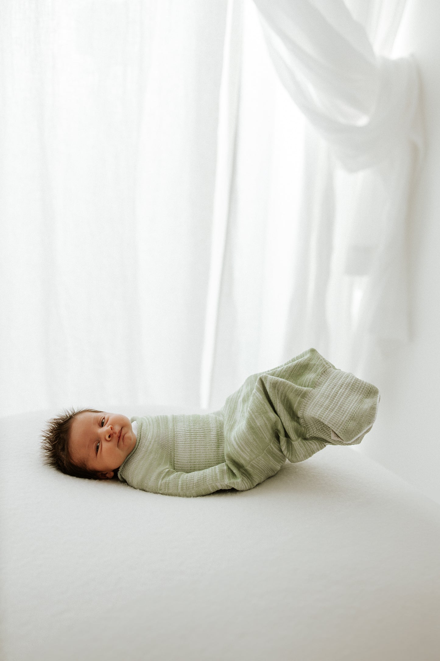 A baby moving around in its infant swaddle.