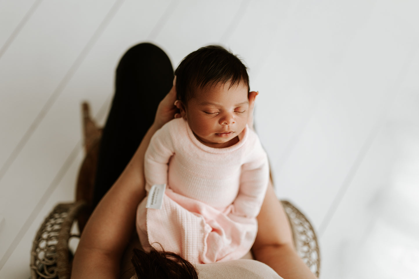 A mother holding her baby in a pink sleep sack.