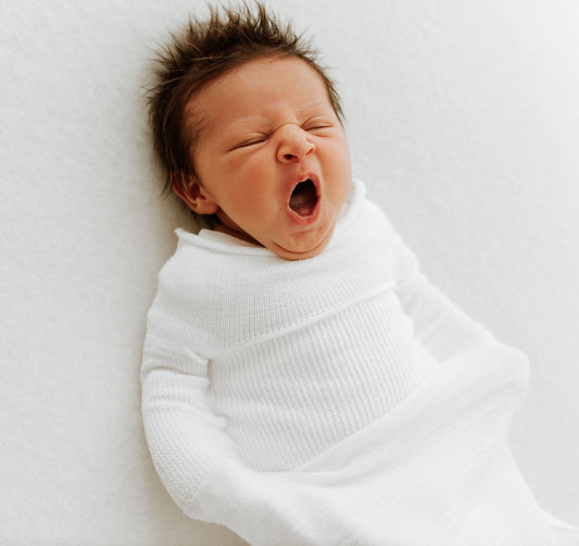 A yawning baby in a bamboo undyed Swaddelini