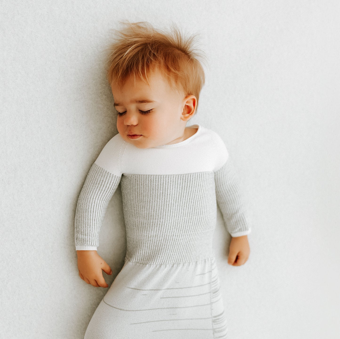 A small toddler in its arms out transition swaddle.
