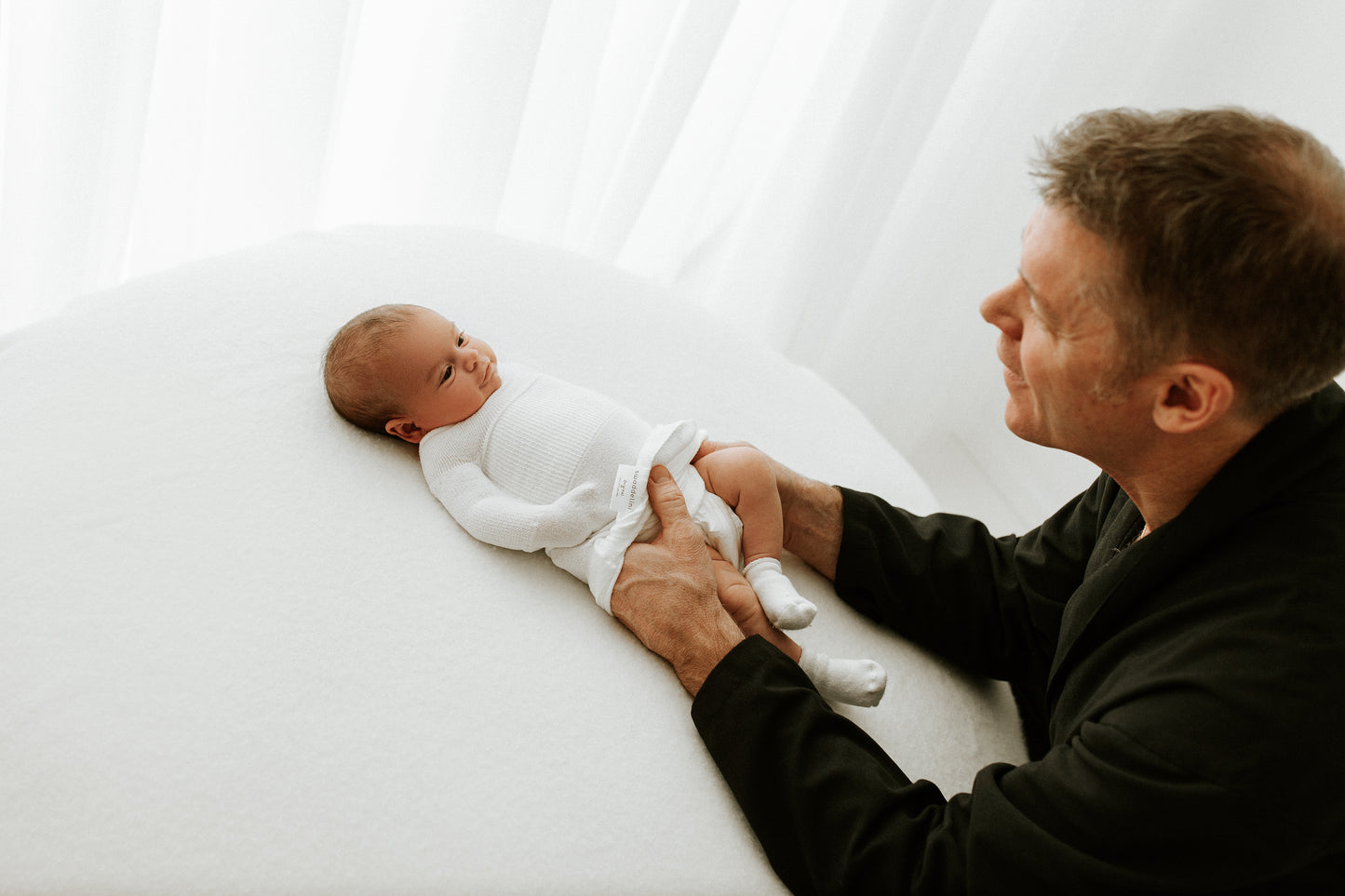 A father putting a swaddle on his preemie baby.