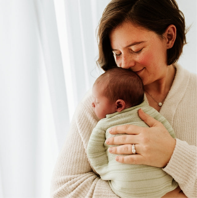 mother holding her swaddled baby