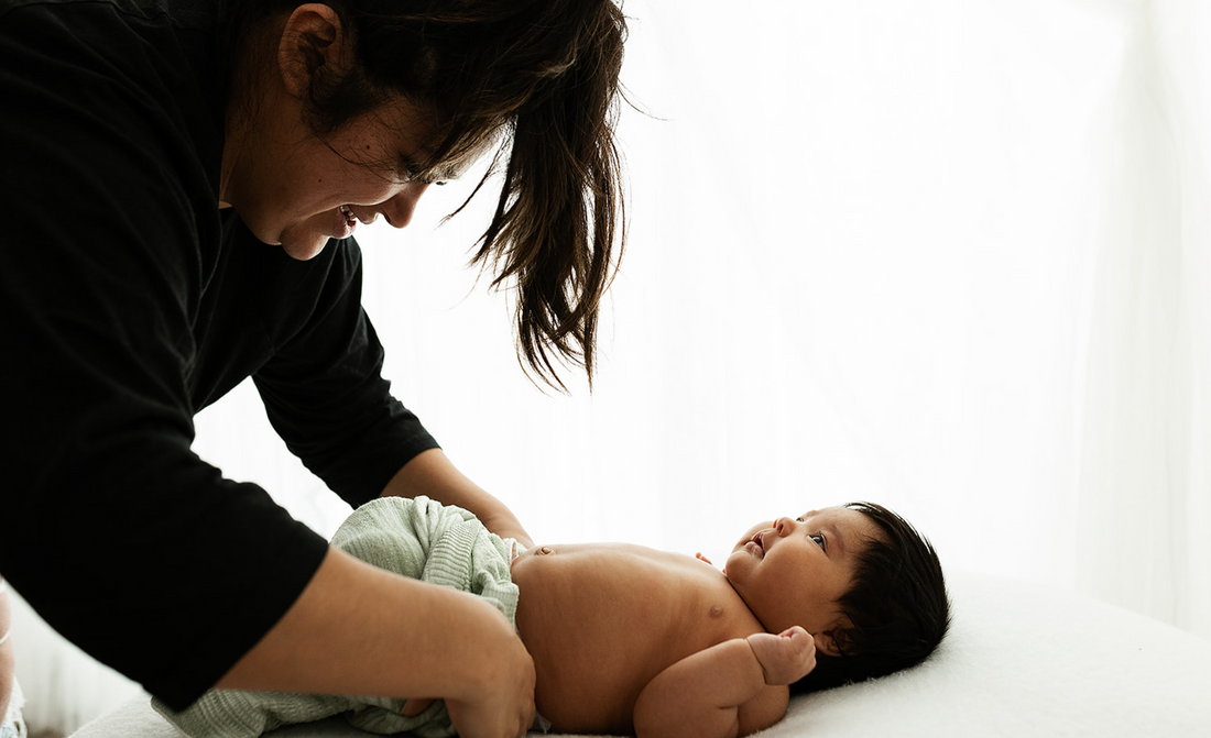 mother putting her baby in a swaddle