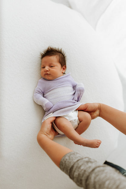 A mother putting her baby in a lavender bamboo sleep sack.