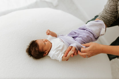 A mom putting a swaddle on her child.