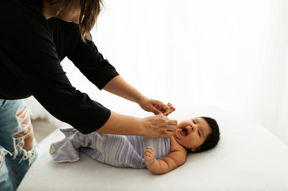 A mother adjusting her baby's swaddle.