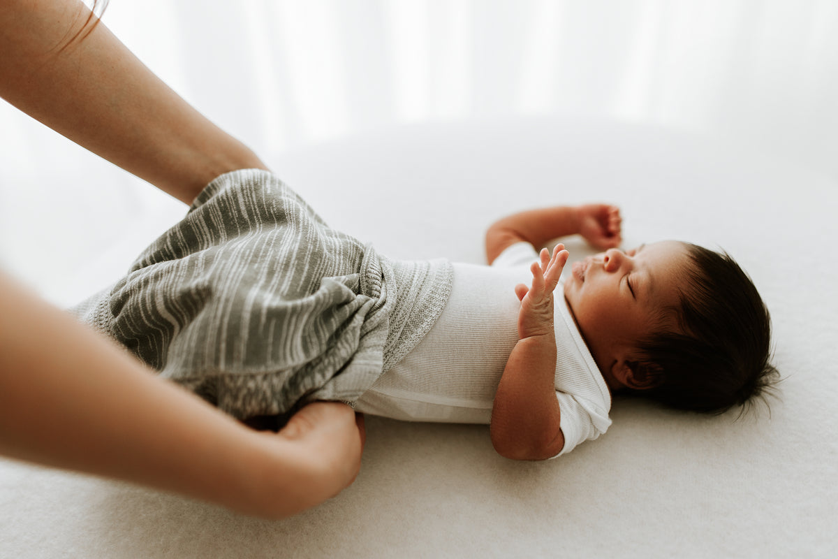 A mother putting a knit sleep sack on her infant.