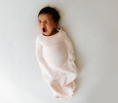 A tired infant in a pink swaddle.