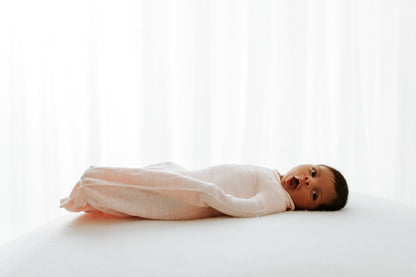 A yawning infant lying in a sleep sack.