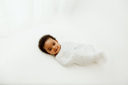 Parent massaging baby using the Swaddelini x Kahlmi Massage Me Swaddle to calm and soothe a crying baby.