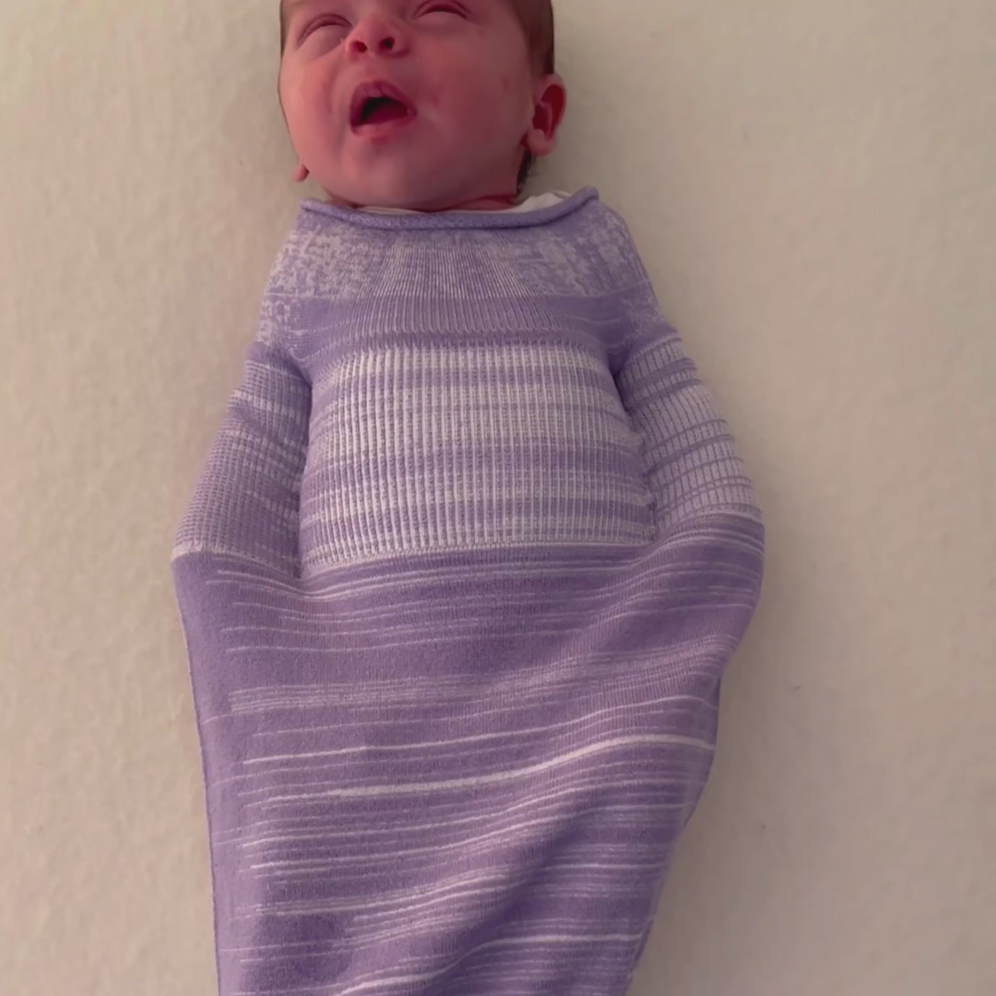 A baby experiencing active sleep in a sleep sack.