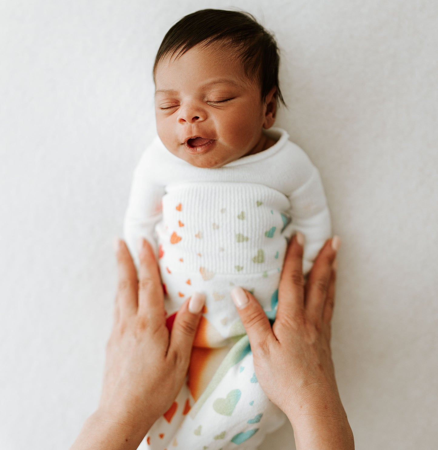 A baby in a rainbow swaddle.